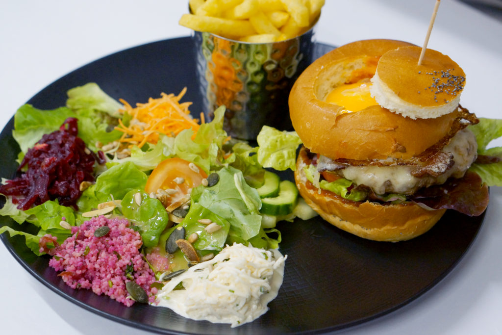 Burger du chef, viande de bœuf, Vacherin, salade, tomates, oignons rouges, sauce tartare et frites.